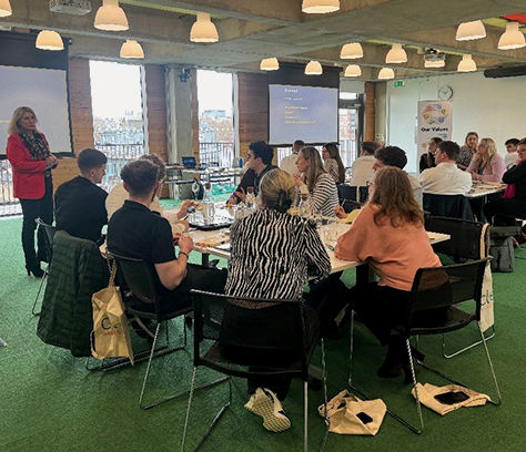 Early Career Professionals. Clear staff members in the Early Career Professionals programme sitting listening at tables listening to a speaker