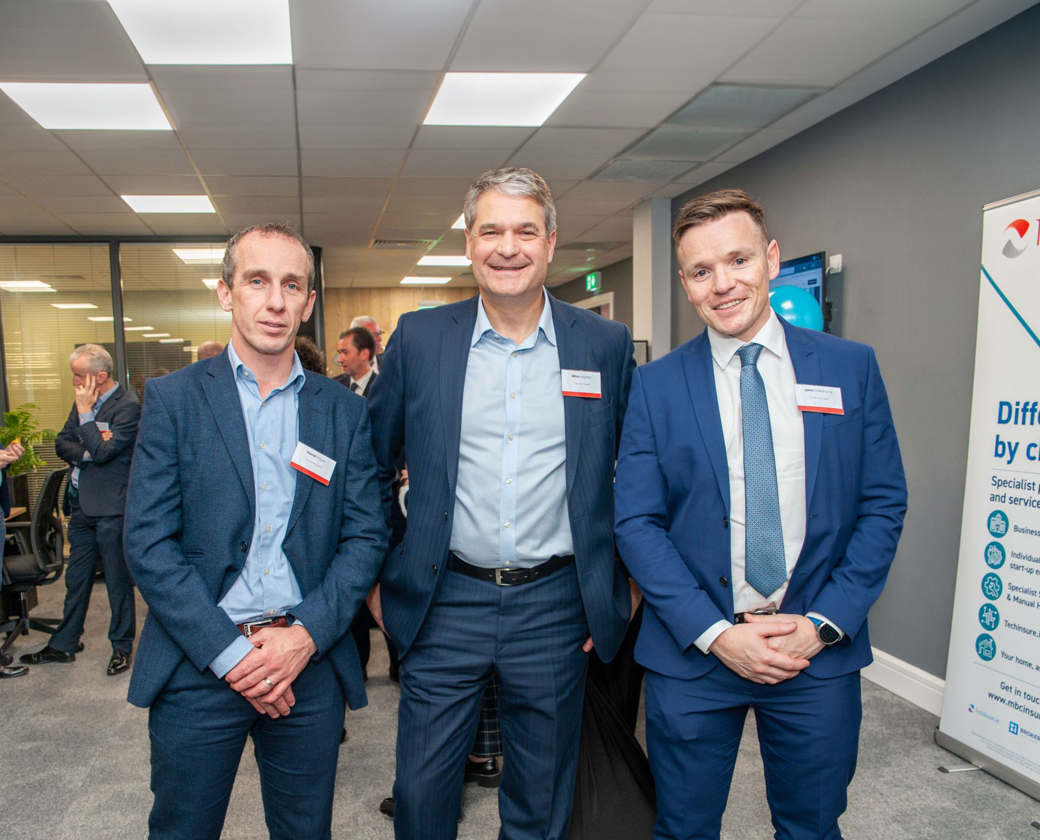 Clear CEO Mike Edgeley at an event standing in a suit with two other suits smiling at the camera