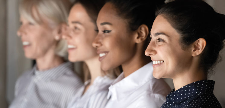 Four smiling, professional, ethnic diverse women looking to the left